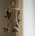 Wooden mobile with hanging animal figurines and leaves against a neutral background