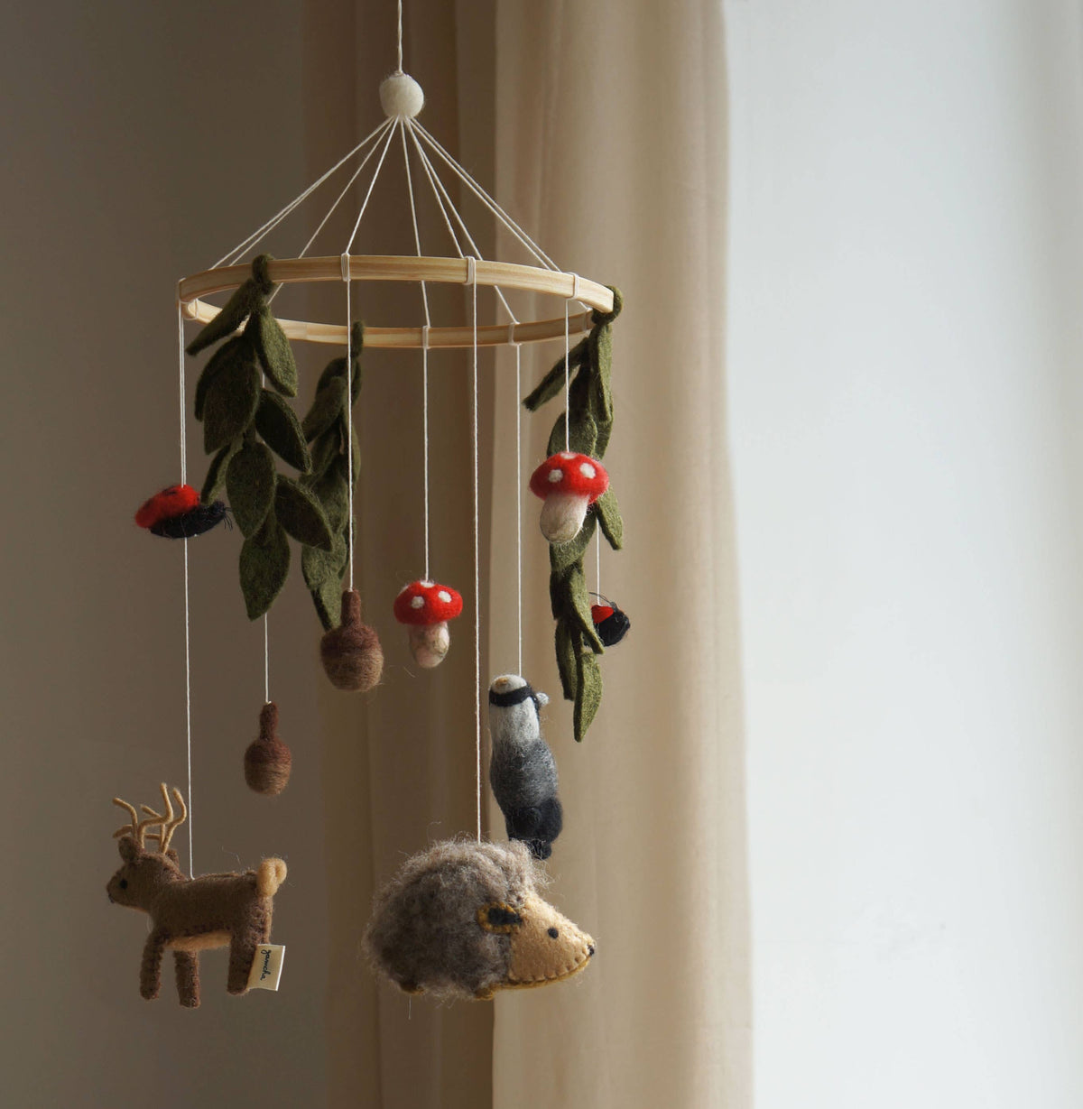 Wooden mobile with hanging animal figurines and leaves against a neutral background