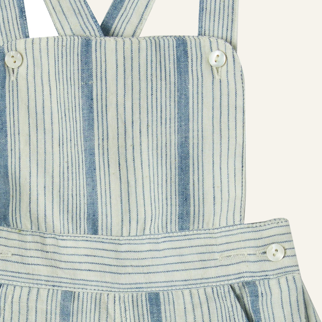 Close-up of a blue and white striped dress with suspenders on a white background