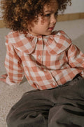 Child wearing a checkered shirt sitting on the floor