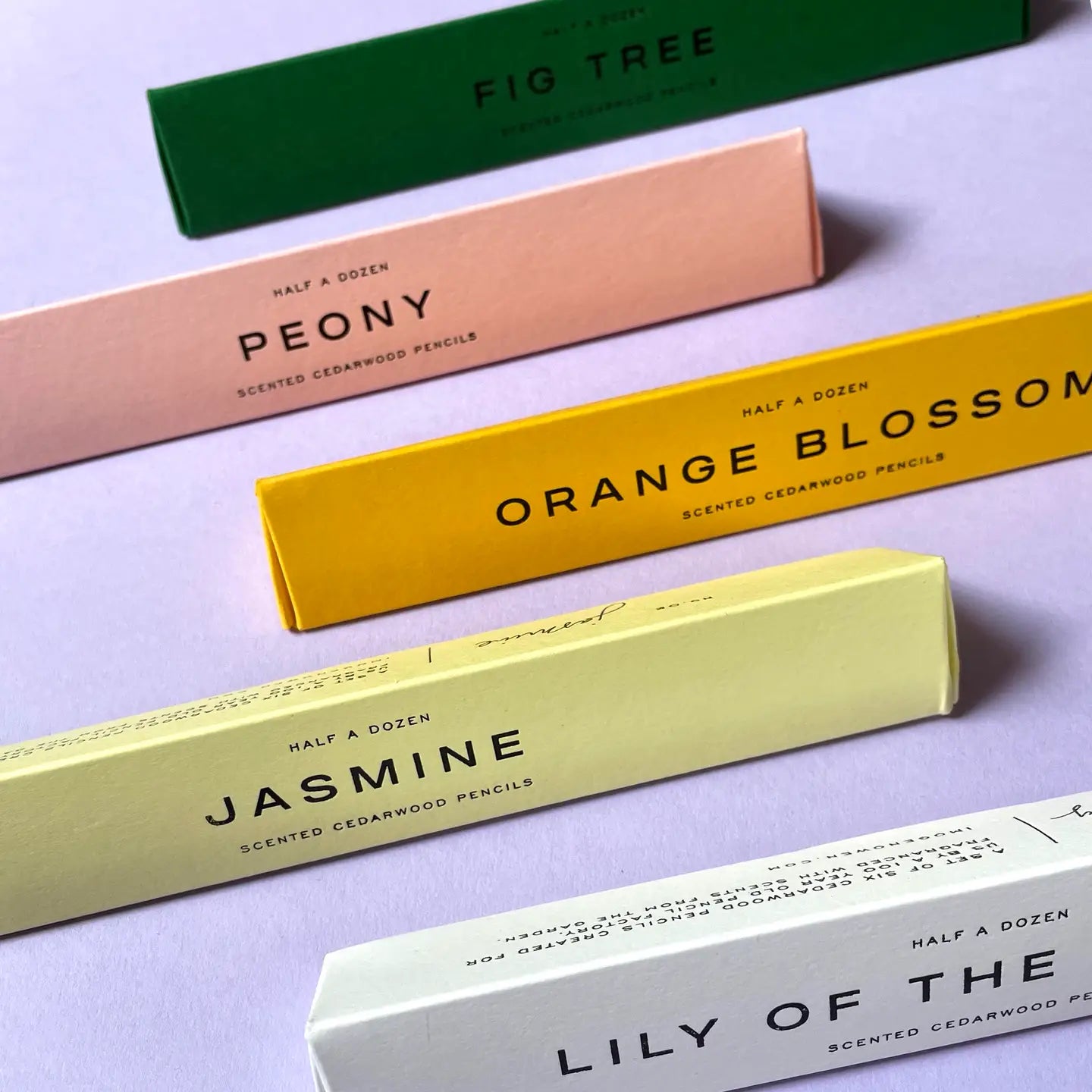 Set of scented cedarwood pencil boxes with names on a light purple background