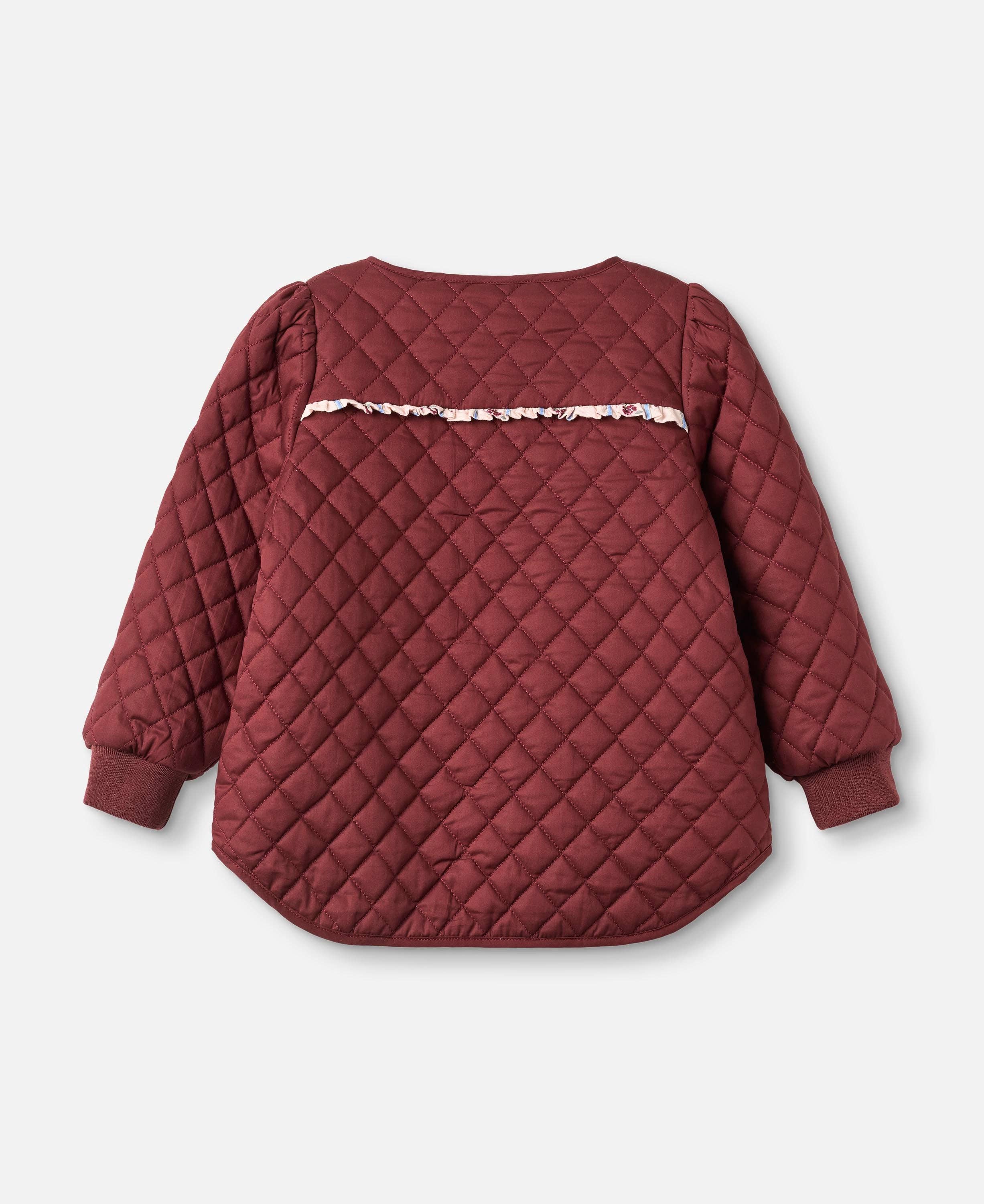 A quilted burgundy children's jacket with a decorative floral ruffle trim across the upper back, shown from the back on a light gray background.