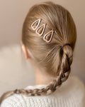 Person with braided hair wearing a gold hair clip against a neutral background