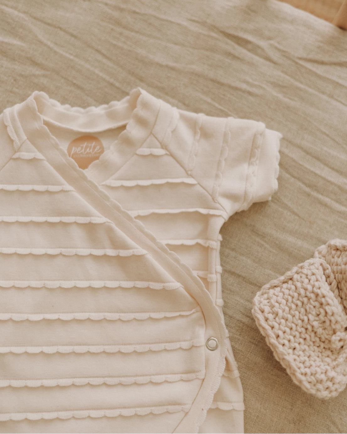 Baby outfit with ruffled design and matching hat on a textured surface