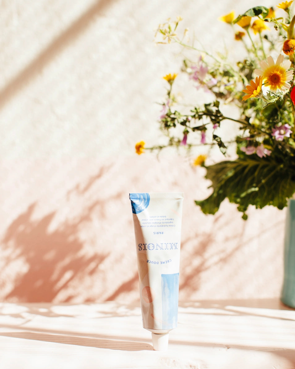 Tube of moisturizer with a bouquet of flowers on a wooden surface