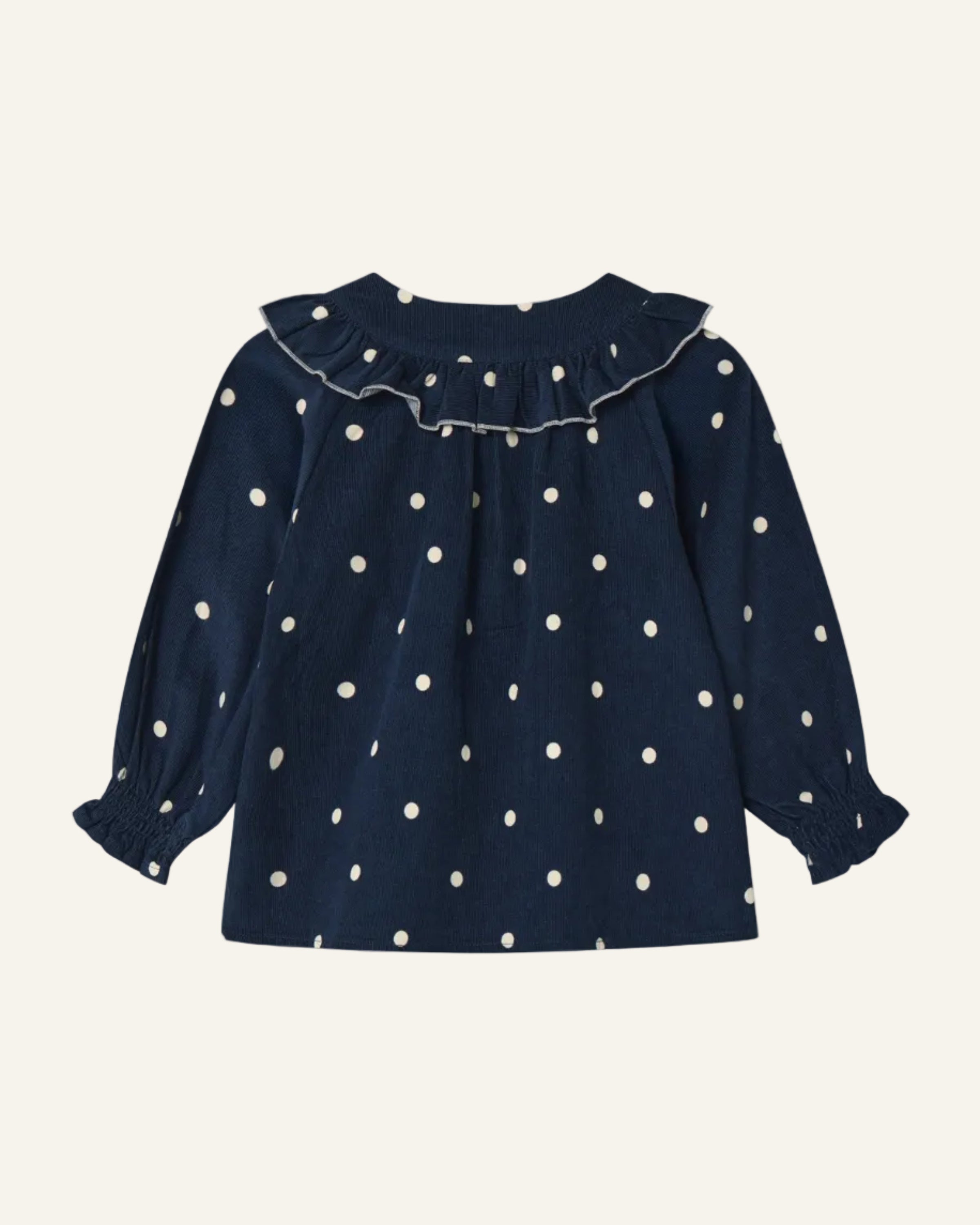 A navy blue long-sleeve blouse for toddlers, featuring a white polka dot pattern, a ruffled collar, and smocked cuffs, shown against a light gray background.