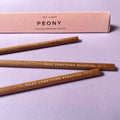 Three wooden pencils with 'Make Something Beautiful' text on a light purple background, accompanied by a pink box labeled 'PEONY'.