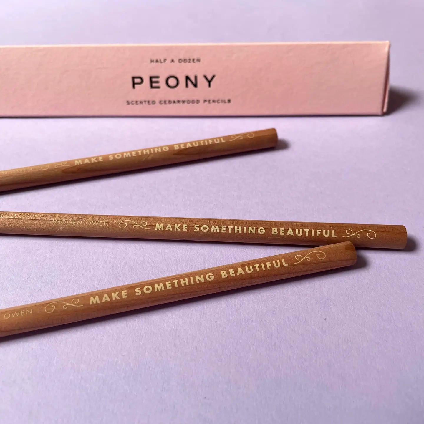 Three wooden pencils with 'Make Something Beautiful' text on a light purple background, accompanied by a pink box labeled 'PEONY'.