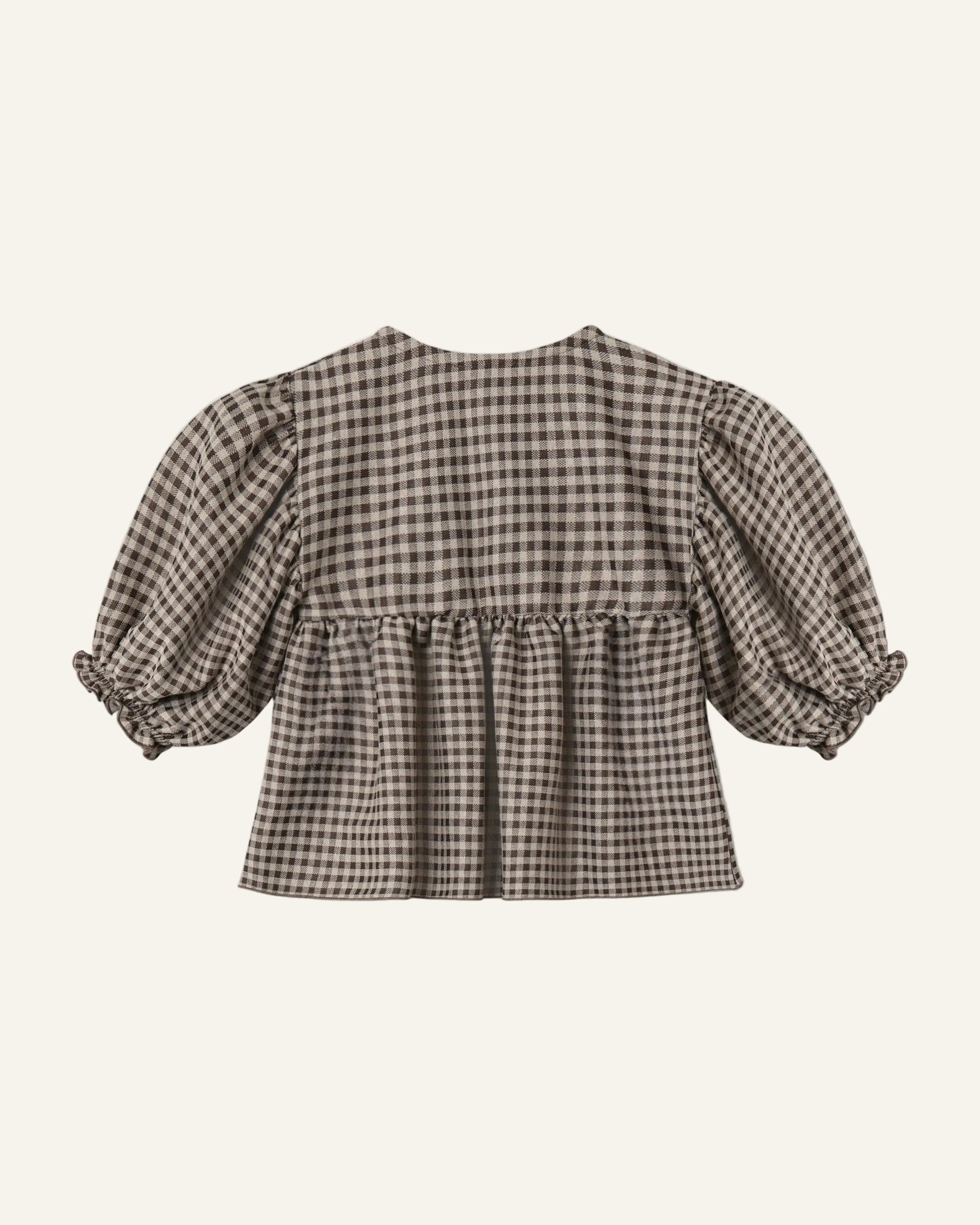 A cropped blouse with a brown and beige gingham pattern, featuring voluminous puff sleeves with ruffled cuffs and a gathered waist seam, shown from the back on a light gray background.